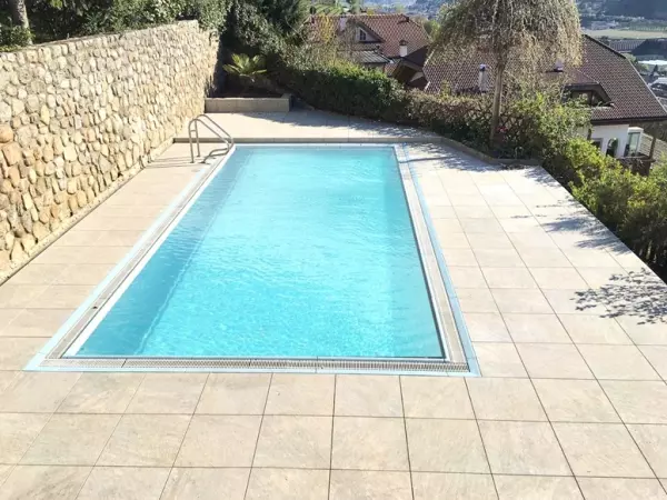 Taras wyłożony płytką beżową o wyglądzie kwarcytu, przy basenie